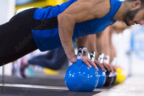 young athletes doing pushups with kettlebells