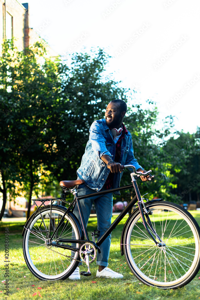 smiling african american man with retro bicycle in park smiling african american man with retro bicycle in park