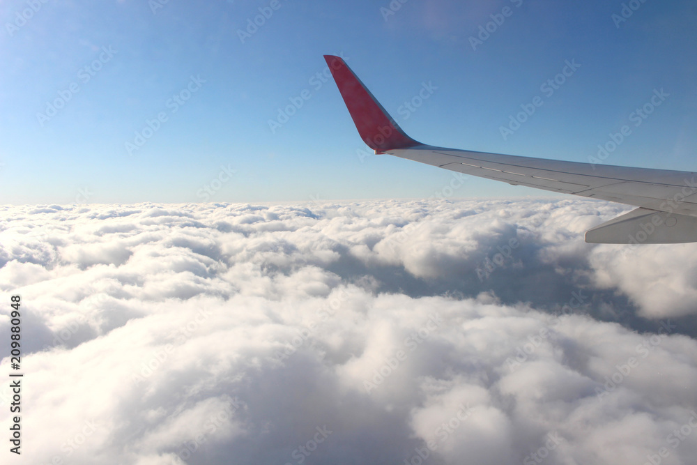 Wing of an airplane flying above the clouds. people looks at the sky from the window of the plane Wing of an airplane flying above the clouds. people looks at the sky from the window of the plane