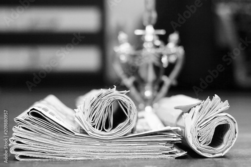 Lots of newspapers folded and rolled in pile and winner cup on background. Tabloid journals with latest news and sensations and trophy prize, concept for winnig and media      photo