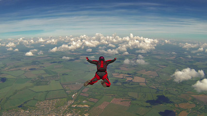 Fotobehang Luchtsport Skydiver in rood pak boven wolken  © vladimirzhoga