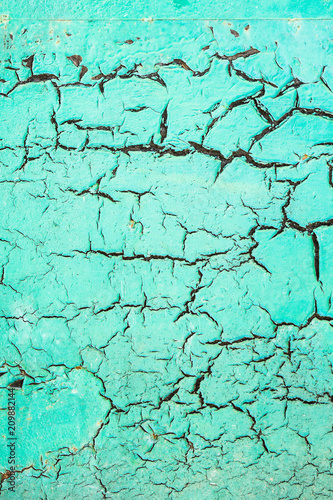 Vintage background of an old cracked wall painted in turquoise color