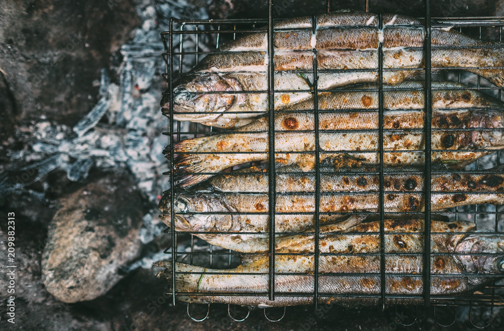 Top view trouts in grilling grid on the fireplace