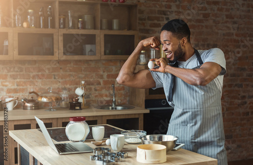 Black man baking cookies and having fun in kitchen photo