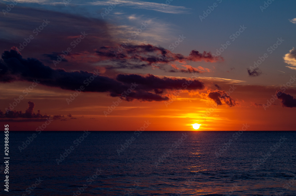 Beautiful sunset at the sea with the sky with some scattered clouds.