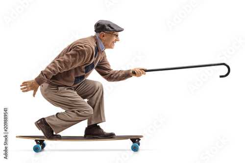 Elderly man riding a longboard and holding a cane