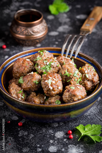 Beef meatballs in bowl with sauce, brown with sesame and parsley, tatsy snack