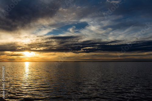 Sunset in the river. Numerous clouds in the sunset. Sky of multiple colors.