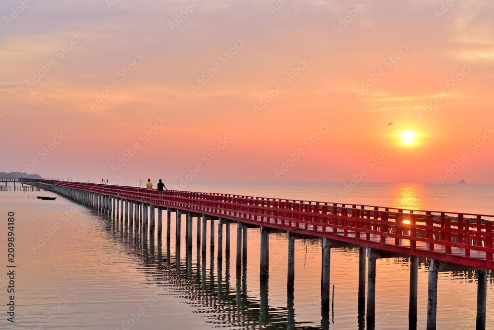 Sunrise and beautiful sky background at wooden red bridge over the sea.