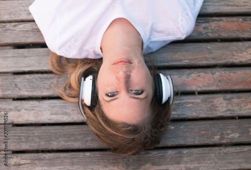 Teenage female listening music outdoor, lying on bench and relaxingб summer photo