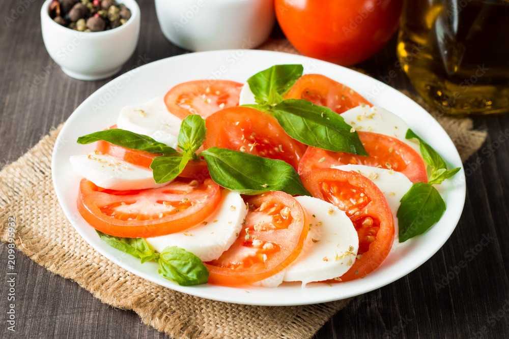 Close-up photo of caprese salad with ripe tomatoes, basil, buffalo mozzarella cheese. Italian and Mediterranean food concept. Fresh and healthy organic meal. Starter and antipasti. 