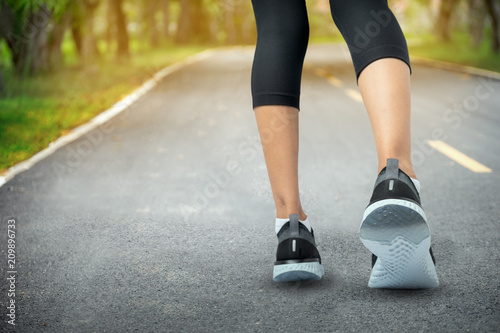 Sports background, Runner feet running on road closeup on shoe, Sport woman running on road at sunrise, Fitness and workout wellness concept.