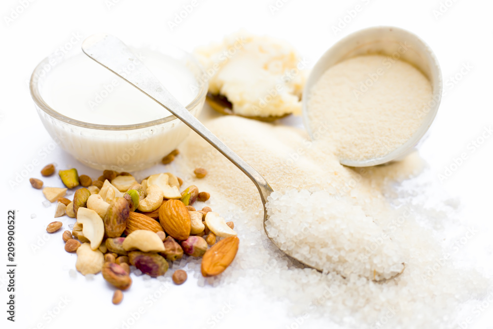Entire ingredients for Suji ka halwa isolated on white including milk and dry fruits.