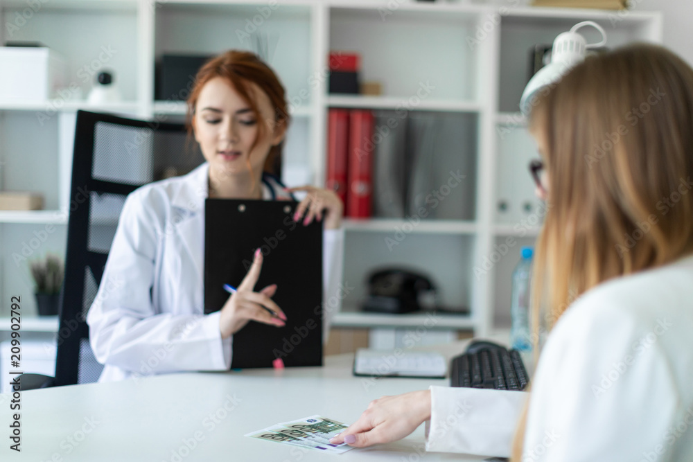 A beautiful young girl in a white robe is sitting at the desk in the office and communicating with the interlocutor. The interlocutor gives the girl money. The girl refuses to take money.