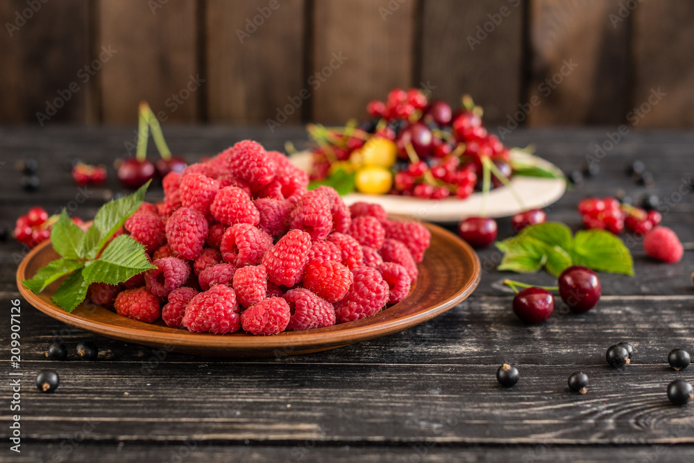 Raspberry, cherry, red currant, blackcurrant on a wooden plate against a dark background. It can be used as a background Raspberry, cherry, red currant, blackcurrant on a wooden plate against a dark background. It can be used as a background