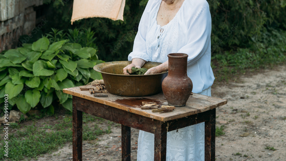 An elderly woman is washing clothes in the garden. in white vintage clothing. country life. clothes dries on a rope. An elderly woman is washing clothes in the garden. in white vintage clothing. country life. clothes dries on a rope.