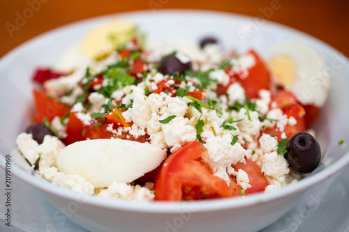Bulgarian salad named Ovcharska Salata: made with tomatoes, cucumbers, Sirene cheese, Greek olives, red onion, parsley, egg and red peppers.
