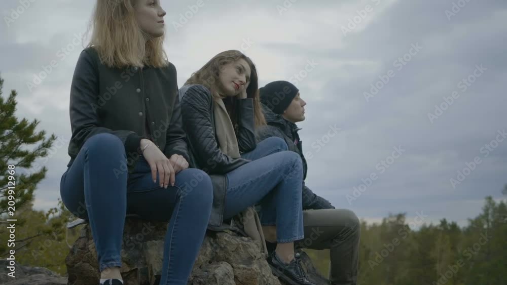 Two girls and a guy are sitting with a pensive look Two girls and a guy are sitting with a pensive look