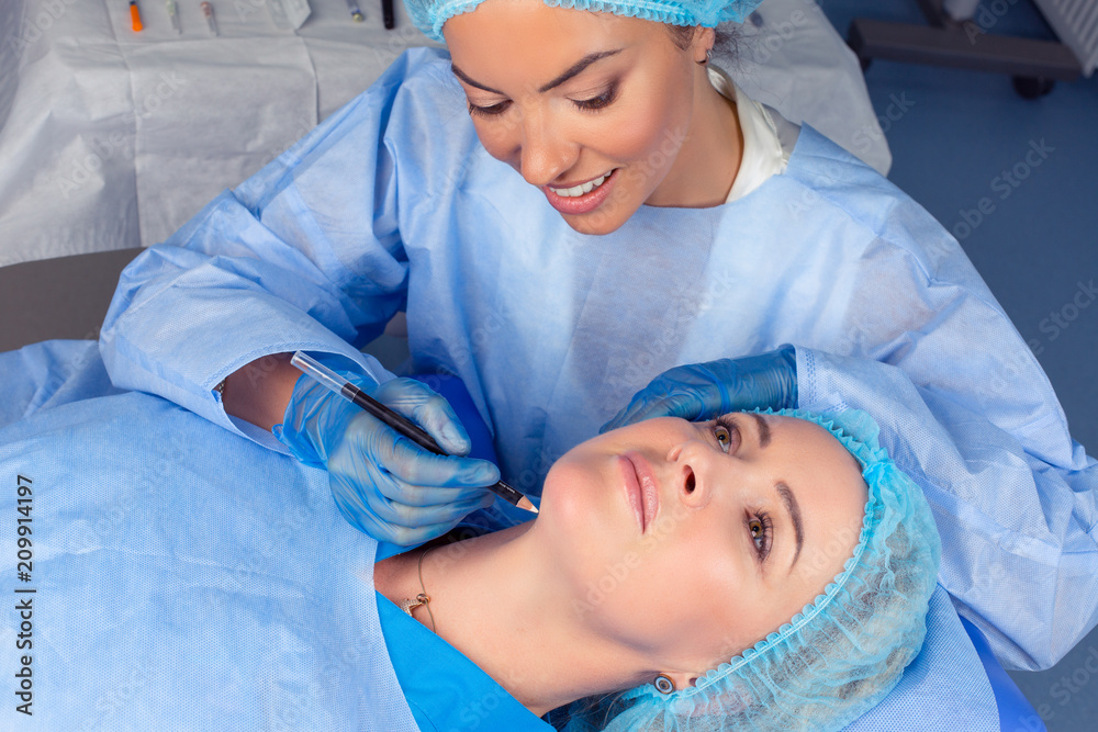 doctor woman is about to draw lift lines on patient neck with pencil doctor woman is about to draw lift lines on patient neck with pencil