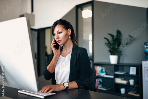 Fotografia Having serious phone conversation with colleague while solving problem on the computer