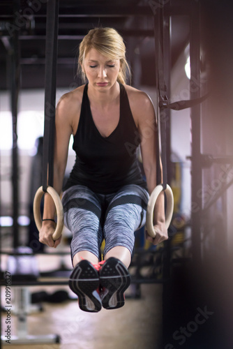 woman working out pull ups with gymnastic rings