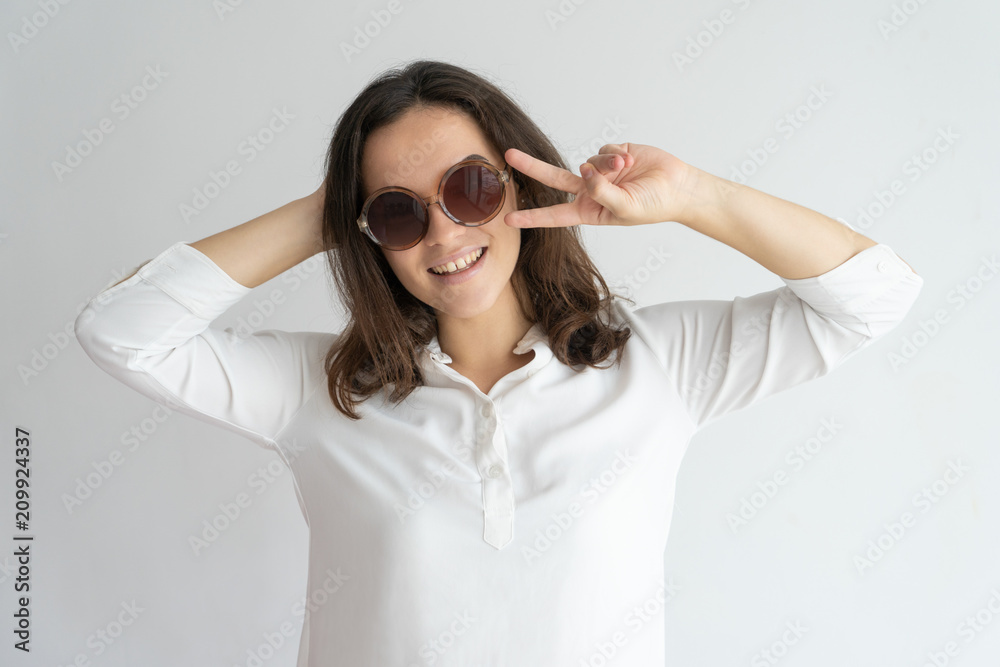 Joyful girl in sunglasses dancing and having fun. Happy young Caucasian woman showing peace or victory sign. Gesturing or party concept Joyful girl in sunglasses dancing and having fun. Happy young Caucasian woman showing peace or victory sign. Gesturing or party concept