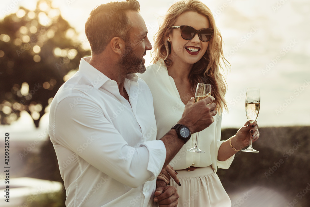 Smiling couple enjoying a glass of wine - obrazy, fototapety, plakaty 