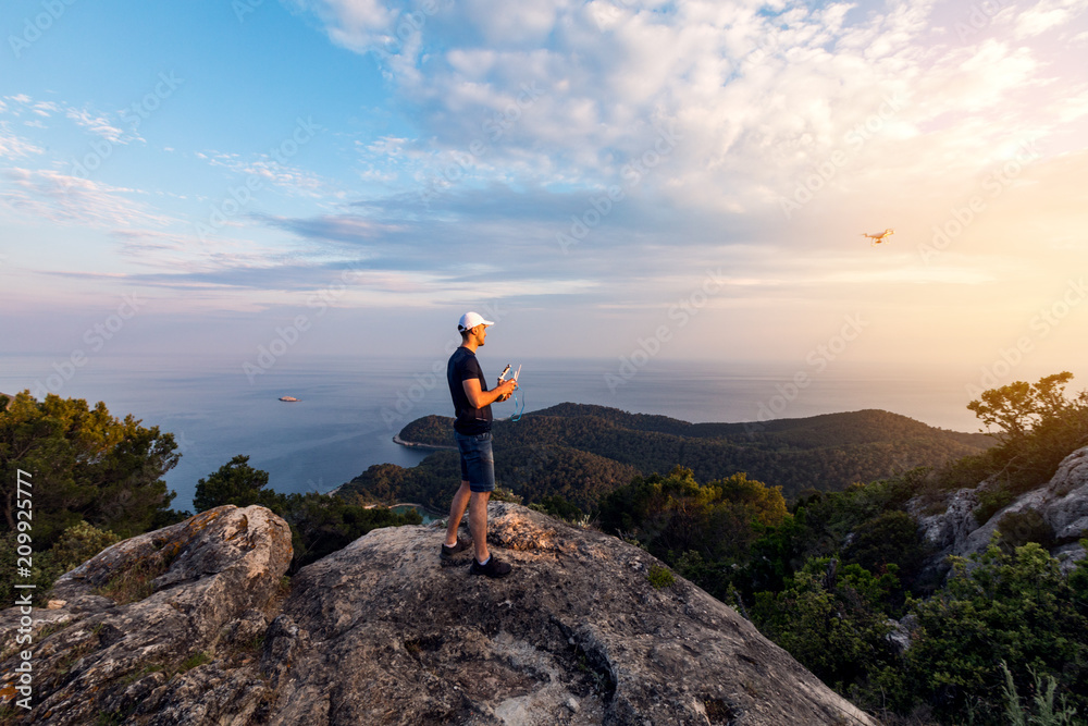 Man operating a drone using a remote controller.Man using drone at sunset for photos and video making 