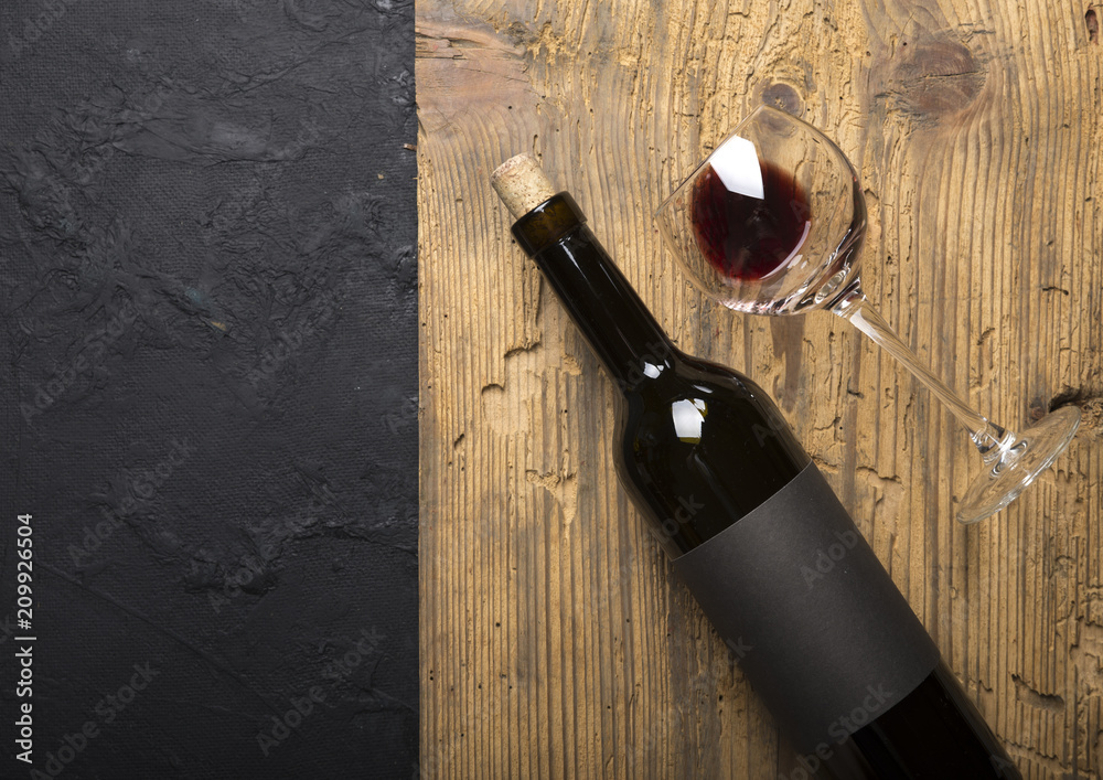 Bottle of red wine with a corkscrew. On a black wooden background.