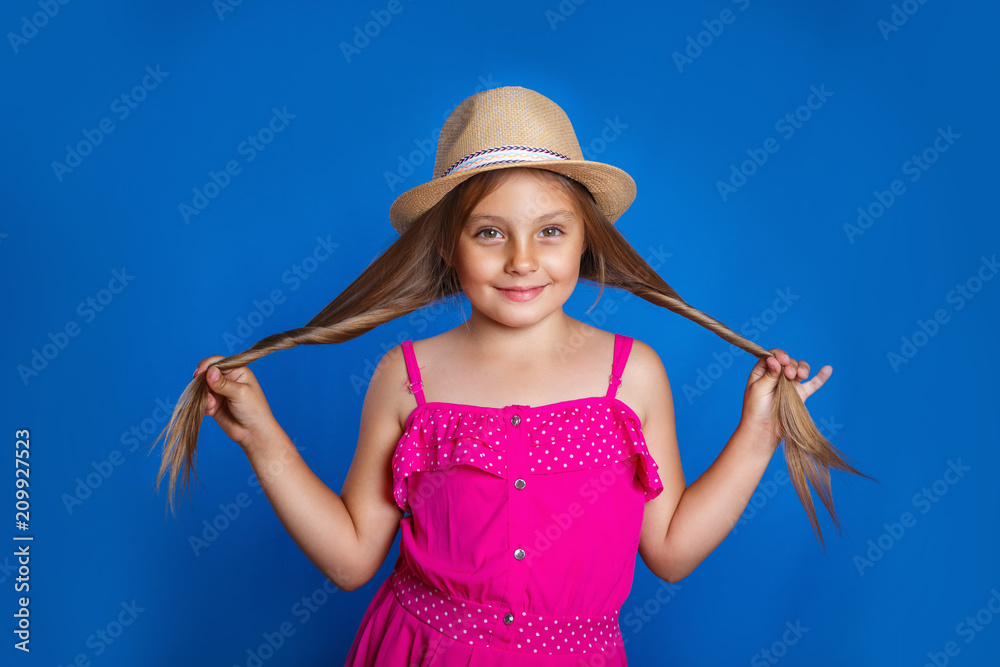 Portrait of young pretty girl in pink dress and hat having fun on blue background . Summer vacation and travel concept Portrait of young pretty girl in pink dress and hat having fun on blue background . Summer vacation and travel concept