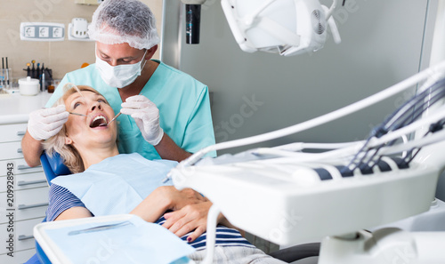 Male dentist treating female patient photo