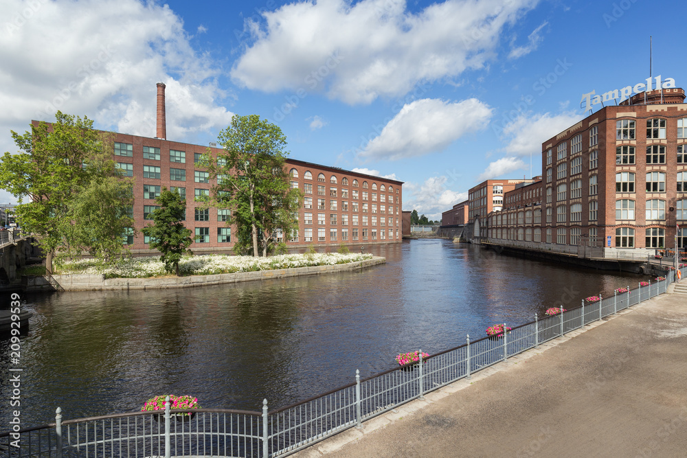 Old red brick industrial buildings along the Tammerkoski rapids in downtown Tampere, Finland on a sunny day. Tampella was an industrial company operating there but now it's a district of the same name