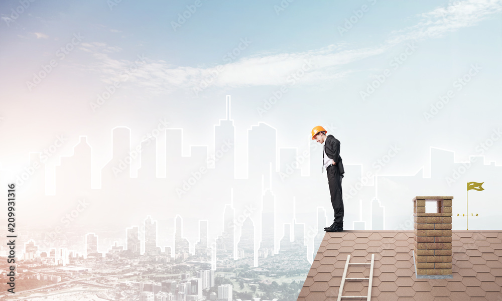 Engineer man standing on roof and looking down. Mixed media Engineer man standing on roof and looking down. Mixed media