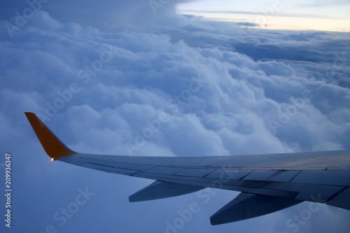 Wing passenger aircraft in flight over the evening clouds
