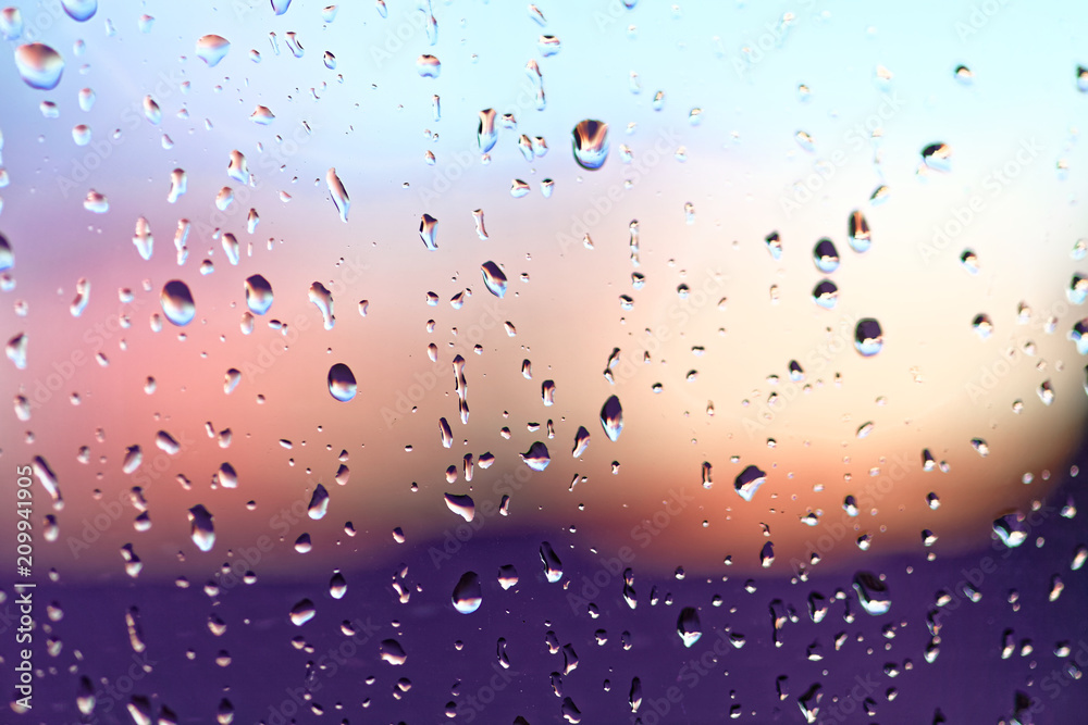 Water rain drops on the window glass on sunset. Shallow depth of field. Cityscape silhouette. Water rain drops on the window glass on sunset. Shallow depth of field. Cityscape silhouette.