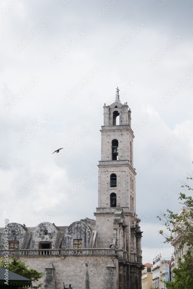 Pigeon flies near the belfry of the Basilica de San Francisco de Asís (Basilica of San Francisco of Asis) in the Plaza of San Francisco, also known as Pigeon Square, in Old Town Havana, Cuba. Pigeon flies near the belfry of the Basilica de San Francisco de Asís (Basilica of San Francisco of Asis) in the Plaza of San Francisco, also known as Pigeon Square, in Old Town Havana, Cuba.