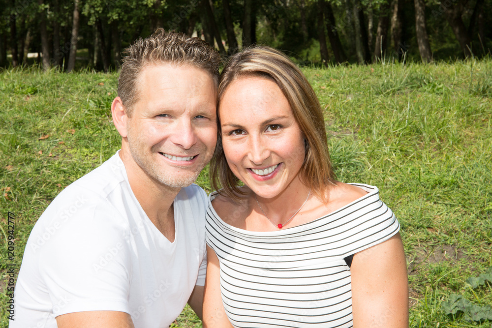 Portrait of loving young couple sit on green grass garden park Portrait of loving young couple sit on green grass garden park