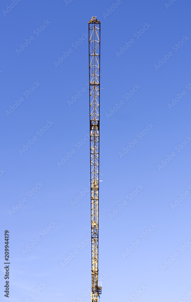 Building construction: Long horizontal jib of a tower crane in front of the blue sky on a sunny winter day Building construction: Long horizontal jib of a tower crane in front of the blue sky on a sunny winter day