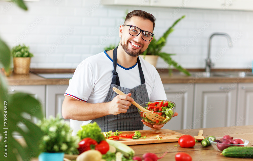 happy man preparing vegetable salad in kitchen happy man preparing vegetable salad in kitchen