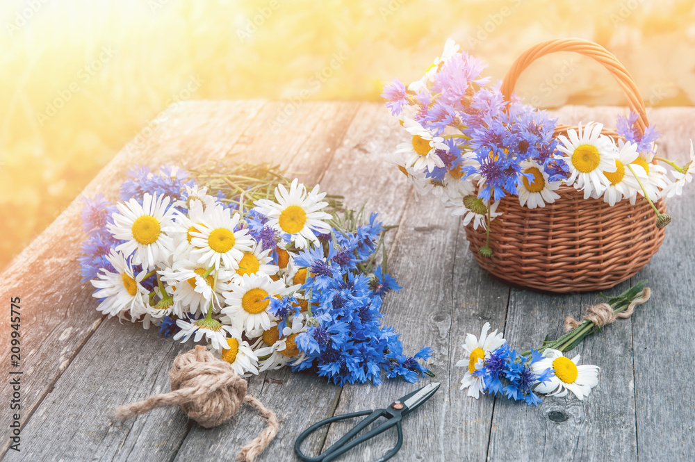 Bouquets of beautiful wild flowers of daisies and cornflowers on a wooden old background. Congratulation.