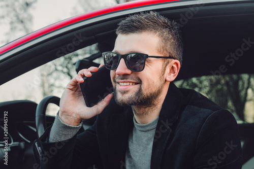 Young handsome man using phone , rich guy sitting in the car
