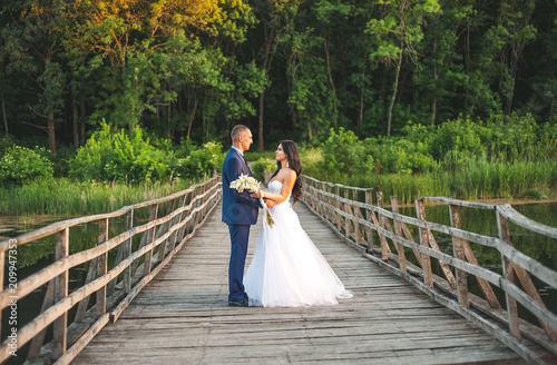 young couple in love, the bride and groom walk along the wooden bridge and look at each other	