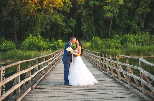 young couple in love, the bride and groom walk along the wooden bridge and look at each other	