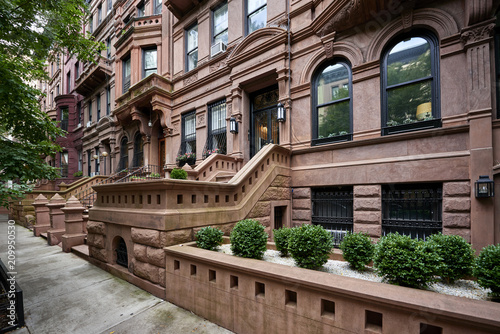 a row of brownstone buildings and stoops in an iconic neighborhood of Manhattan, New York City.