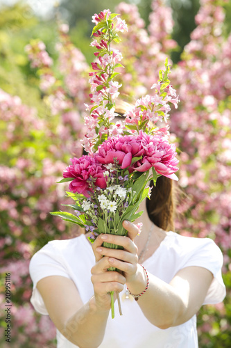 Young woman with bouquet in the garden