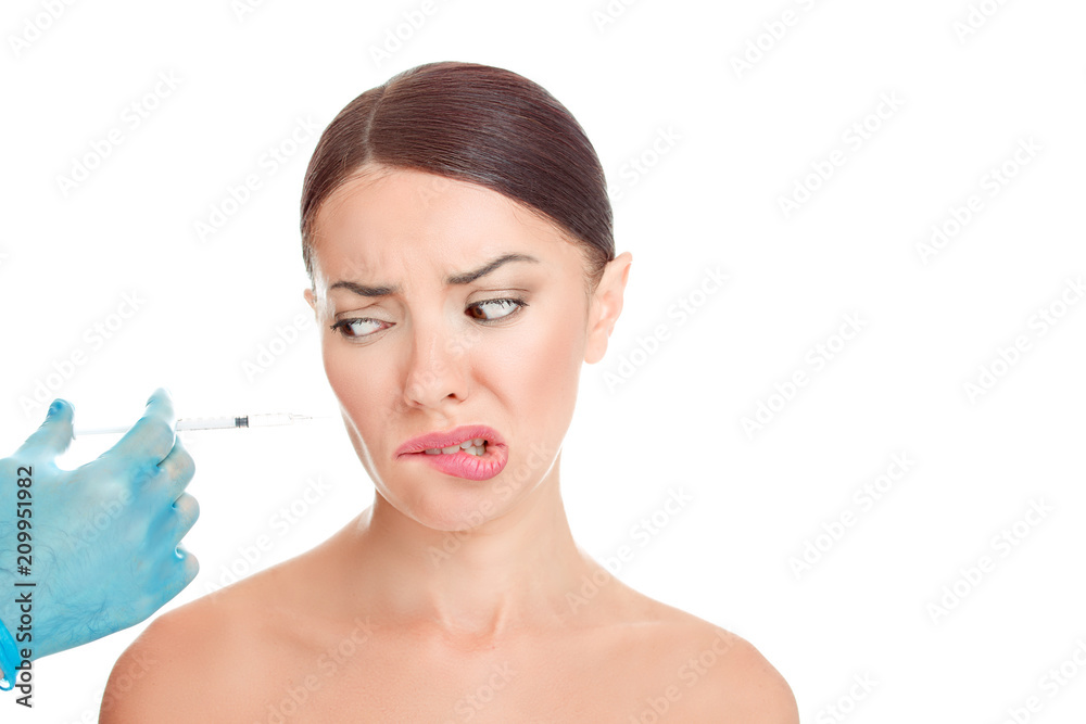 Woman looks to the syringe, is afraid of doctor, syringe, aesthetic surgery