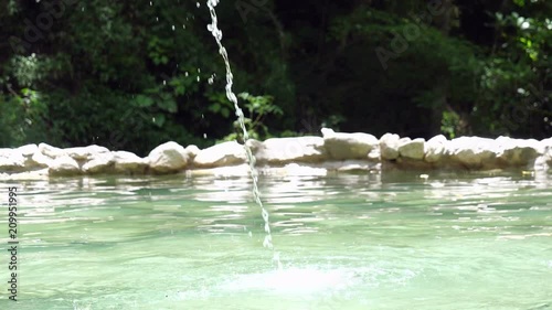 Slow motion splasing water jet in a hot springs in the Caribbean.  Slow motion falling water over a thermal pool in Acosta hot springs in Costa Rica. Water splashing in a holiday spa. photo