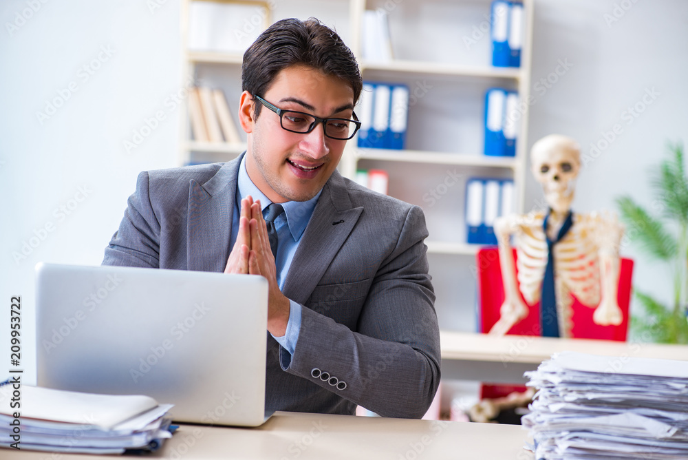 Businessman working with skeleton in office Businessman working with skeleton in office