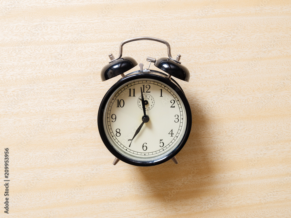 Black retro alarm clock on wooden table. Natural light Black retro alarm clock on wooden table. Natural light
