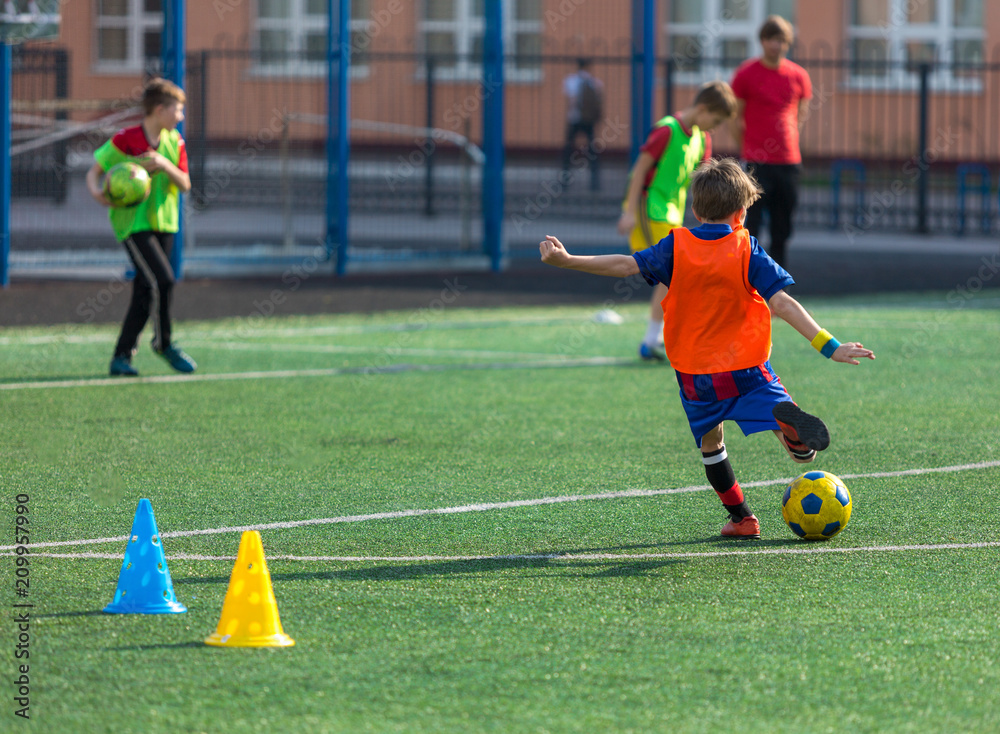 Obraz premium Cute boy playing football, happy child enjoying soccer. Kids activities, little footballer. training on the field in the summer